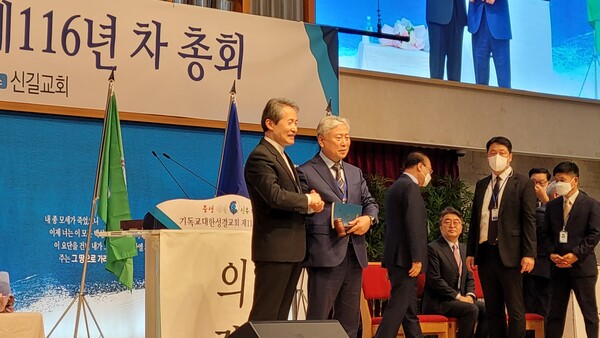 지형은 직전 총회장(왼쪽)이 김주헌 신임 총회장에게 의사봉과 헌법을 전달하고 있다.@데일리굿뉴스