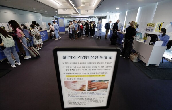 ▲인천국제공항 제1터미널 입국장에 해외입국자들이 검역을 받기 위해 대기하고 있다. 승객들 앞에는 원숭이두창 관련 안내문이 세워져 있다.(사진출처=연합뉴스)