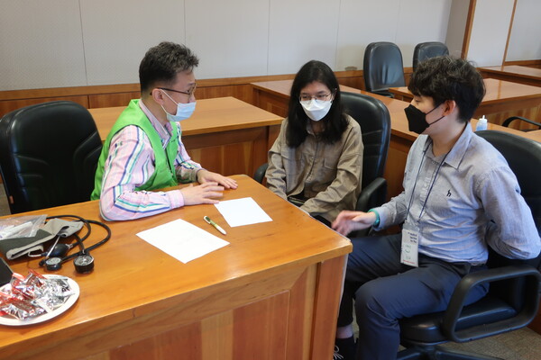 ▲등이 아픈 외국인 유학생에게 통증 원인을 가르쳐주고 있는 의료진과 통역하는 외대교회 청년. ⓒ데일리굿뉴스