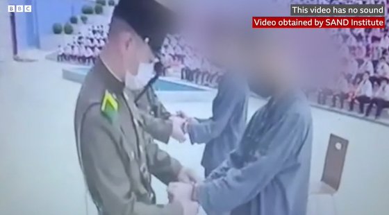 북한 10대 두 명이 한국 TV 프로그램을 시청했다는 이유로 수백명이 지켜보는 공개장소에서 수갑을 차는 모습.(사진출처=BBC 화면 캡처)